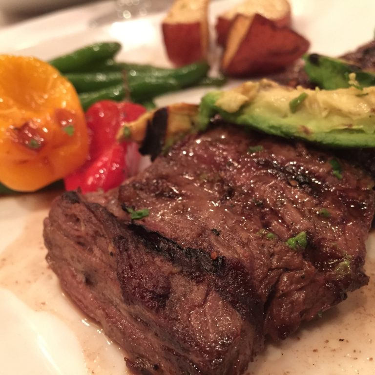 skirt steak on a plate with grilled or roasted vegetables